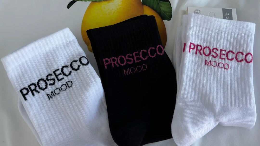White and black Prosecco Mood statement socks styled with lemons for a playful summer fashion look.