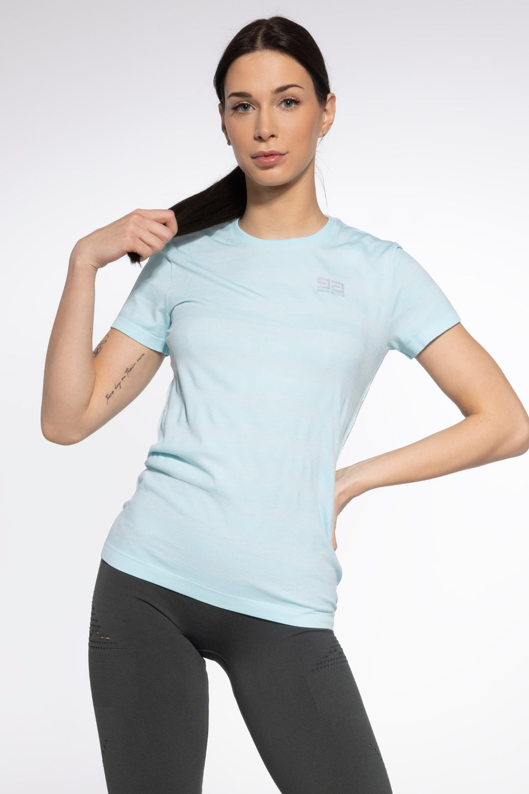 Sporty woman wearing baby blue athletic T-shirt made with quick-dry performance fabric and ergonomic seams, designed for comfort and mobility
