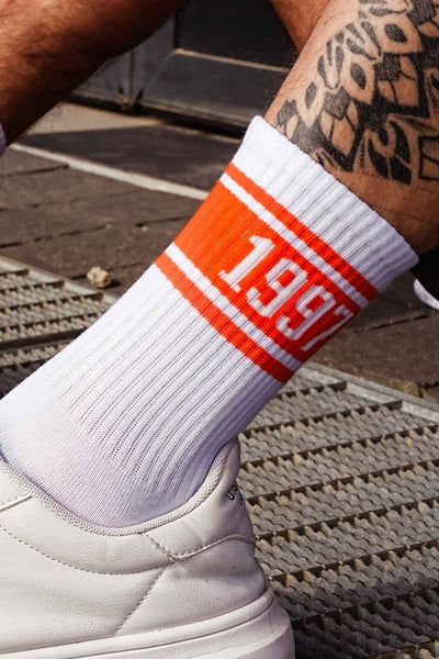Close-up of white and orange men's cotton socks – 1997 retro print detail on soft breathable fabric
