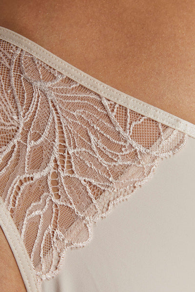 Close-up of the Femme panty's ivory floral lace scalloped over sheer mesh at the hip.
