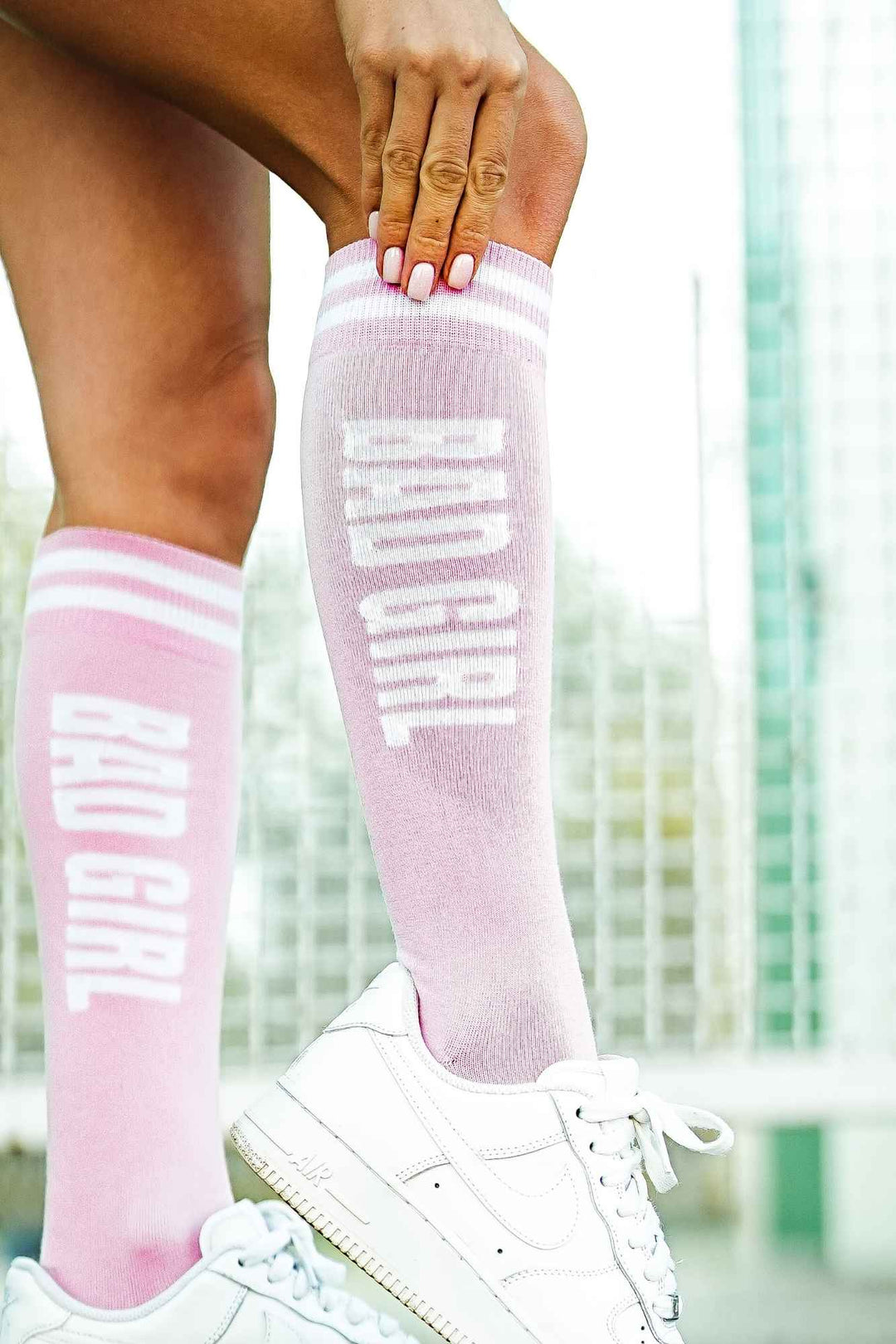 Close-up of powder pink "Bad Girl" knee socks – bold lettering detail on soft cotton fabric
