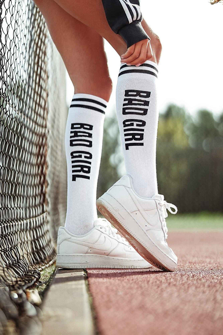 White and black "Bad Girl" cotton knee socks – second side angle showing slogan and length
