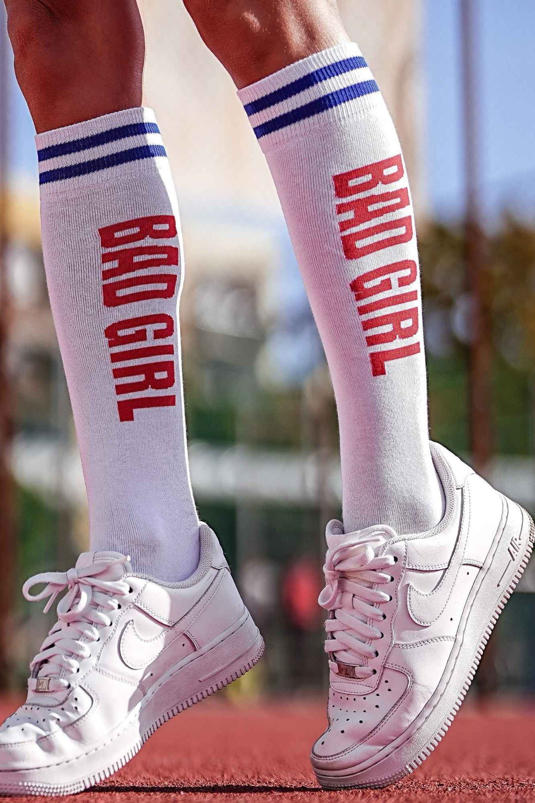 Close-up of white and red "Bad Girl" knee socks – bold lettering detail on soft cotton fabric
