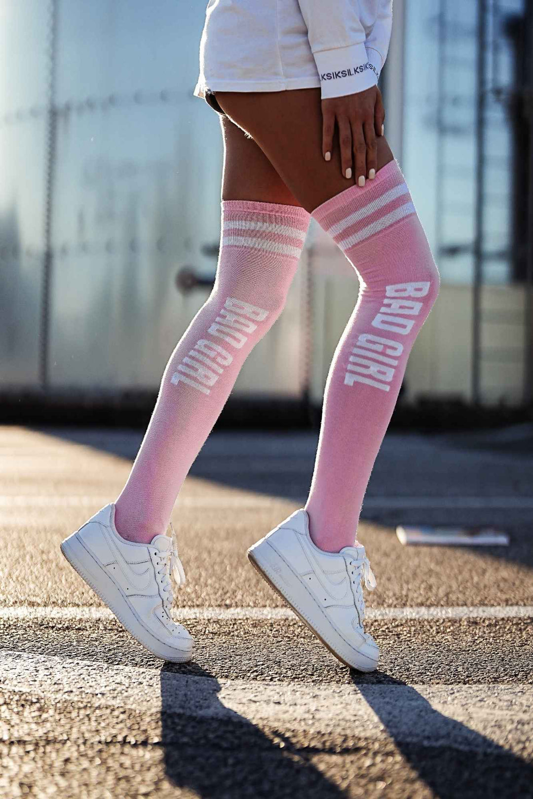 Powder pink "Bad Girl" cotton over-knee socks – side view showing slogan print and full length
