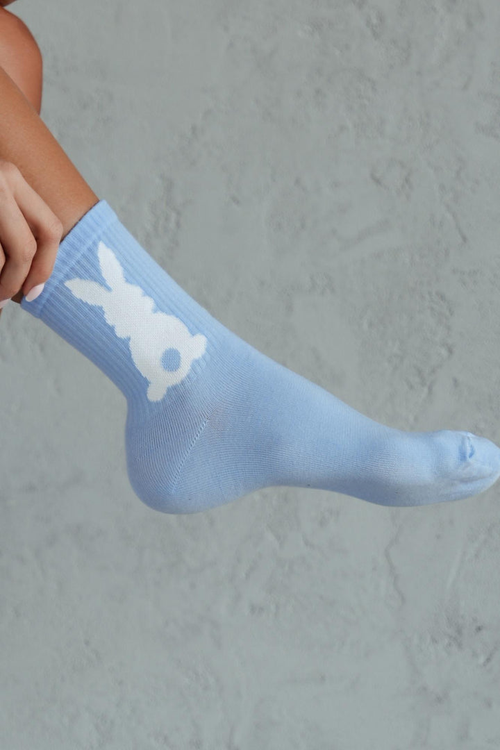 Close-up of blue cotton socks with bunny tail – fluffy tail detail on soft breathable fabric
