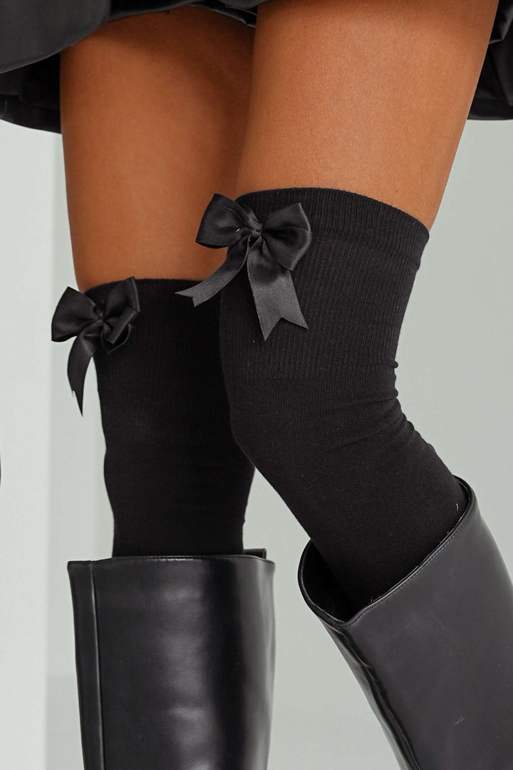 Close-up of white cotton over-knee socks – oversized bow detail on soft breathable fabric
