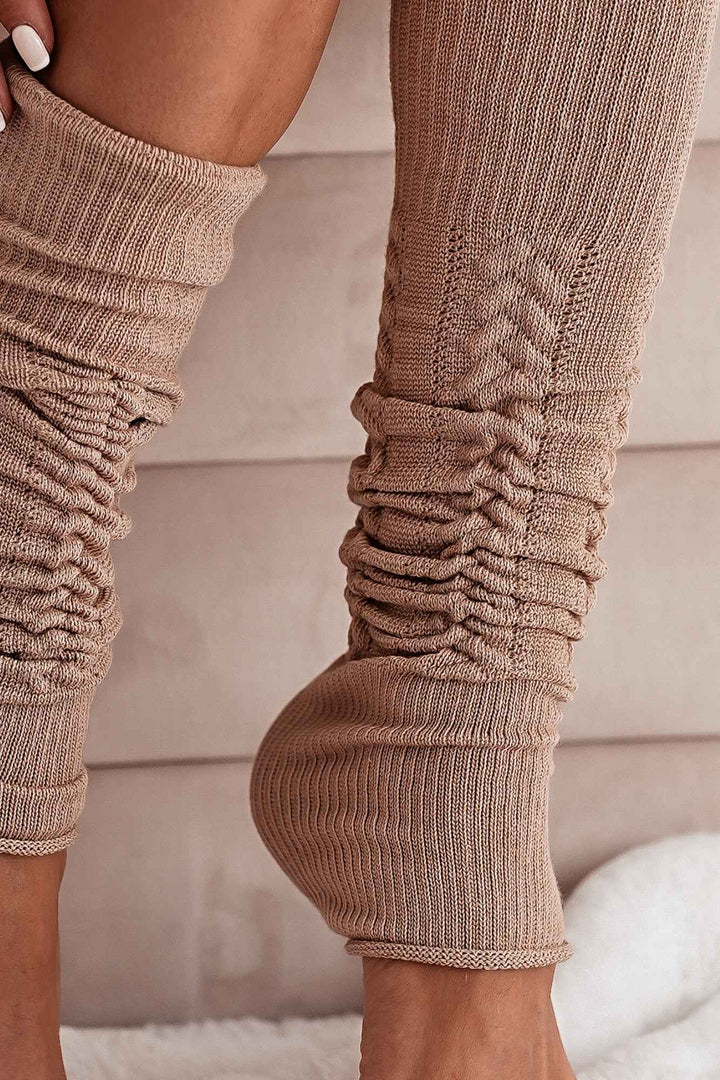 Close-up of beige openwork leg warmers – intricate cotton knit pattern and soft fabric finish
