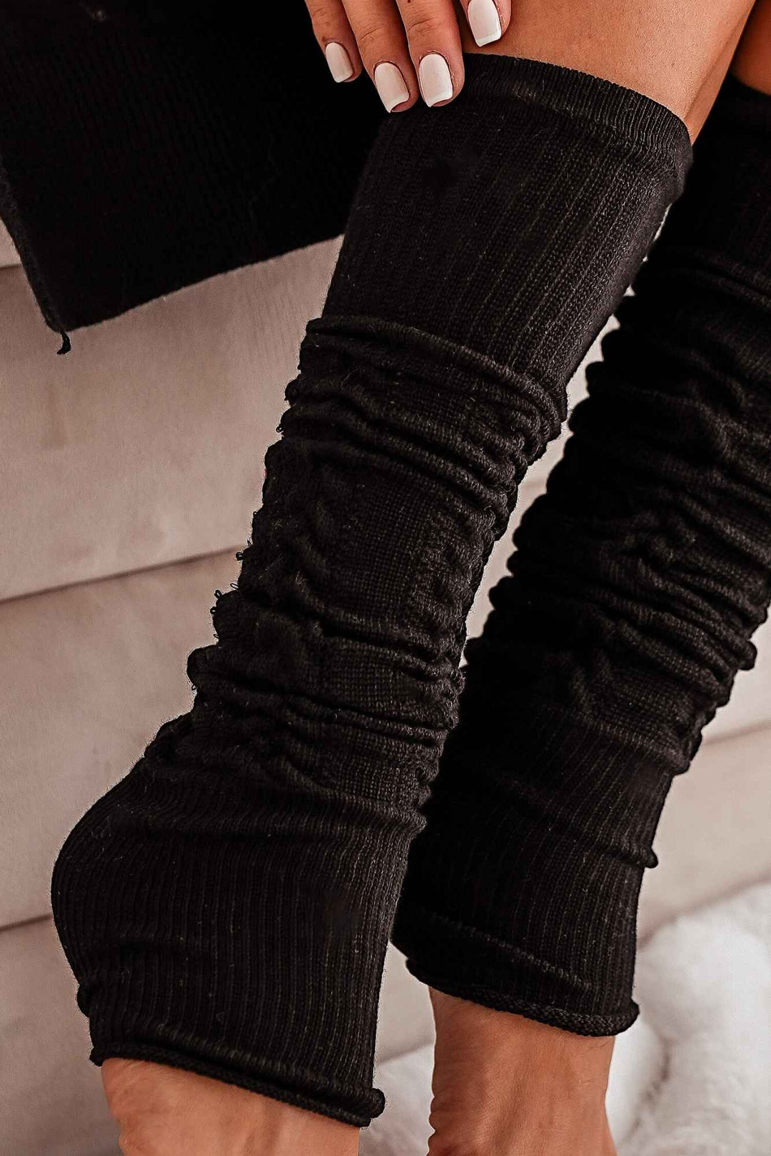 Close-up of black openwork leg warmers – intricate cotton knit pattern and soft fabric finish
