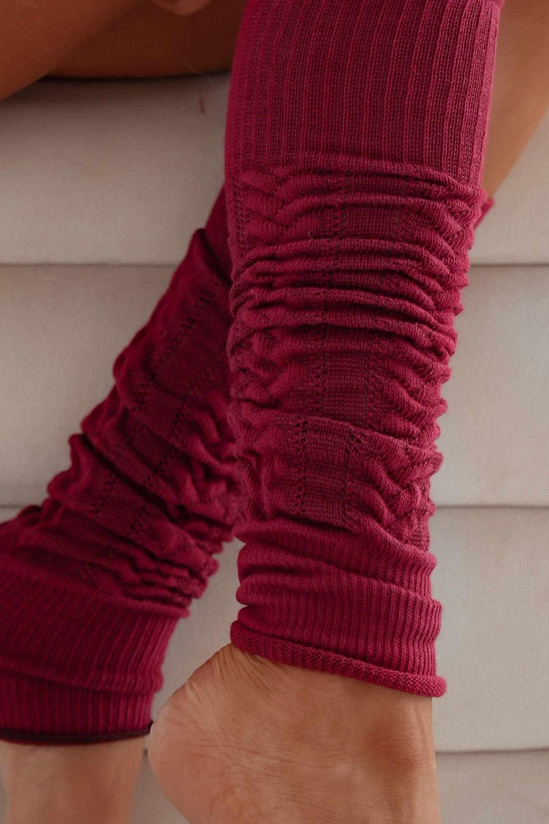 Close-up of claret openwork leg warmers – intricate cotton knit pattern and soft fabric finish
