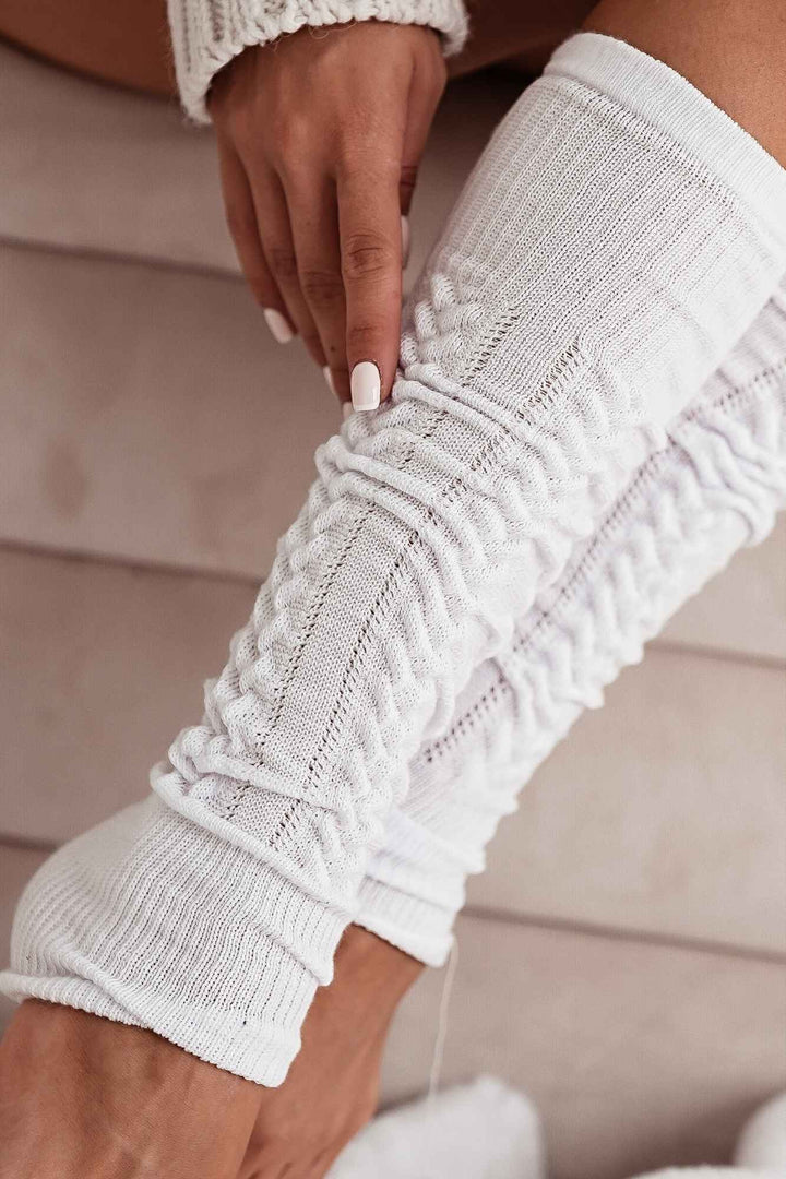 Close-up of white openwork leg warmers – intricate cotton knit pattern and soft fabric finish
