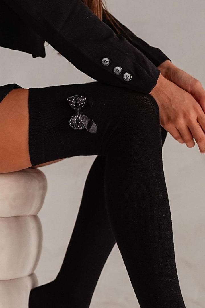 Close-up of black cotton over-knee socks – bow detail on soft breathable fabric
