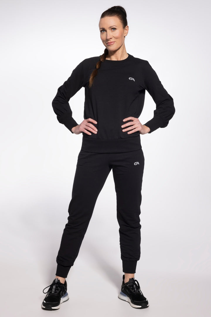 Woman wearing a black tracksuit with a logo on a white background