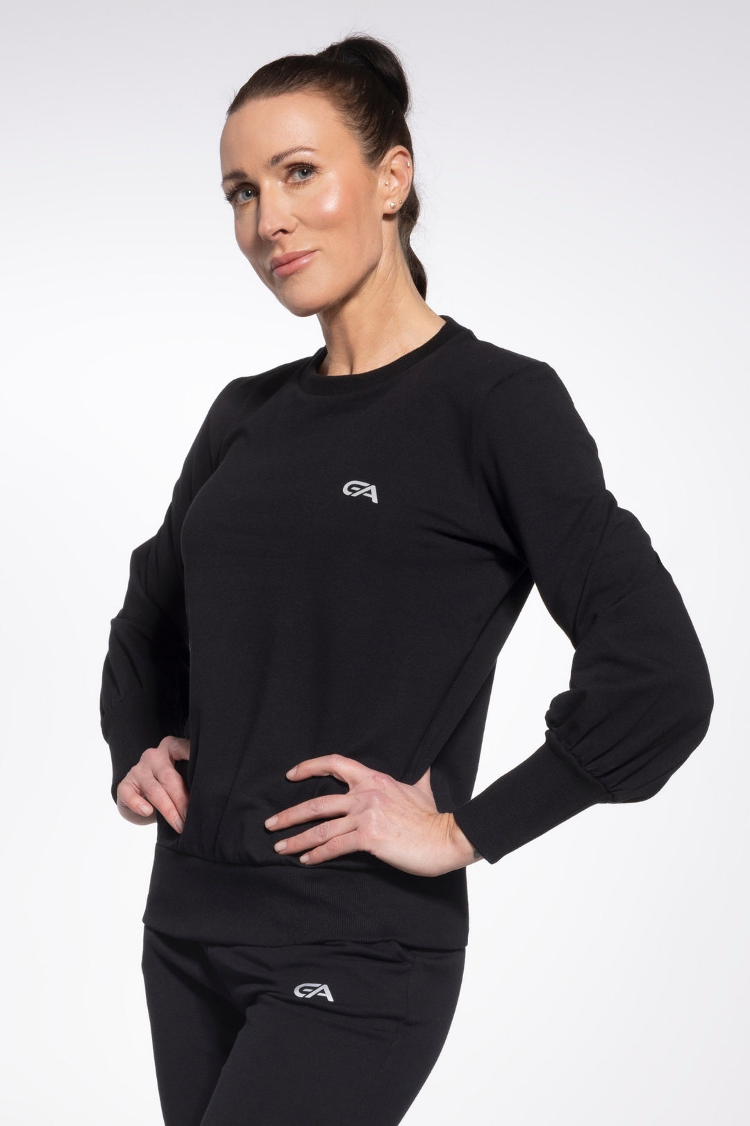 Woman wearing a black long-sleeve athletic top with a logo on a white background