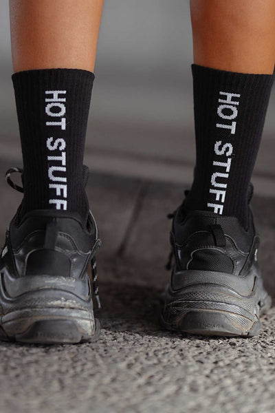 Close-up of black cotton socks with "Hot Stuff" slogan – bold lettering on soft breathable fabric
