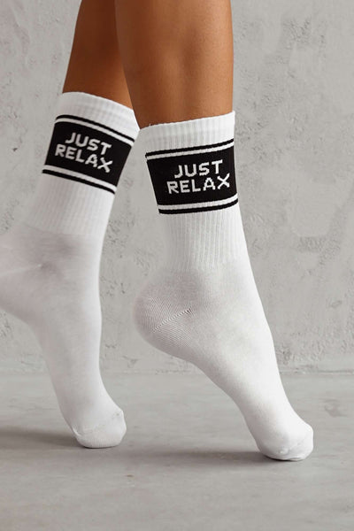 Close-up of white cotton socks with "Just Relax" slogan – bold lettering on soft fabric
