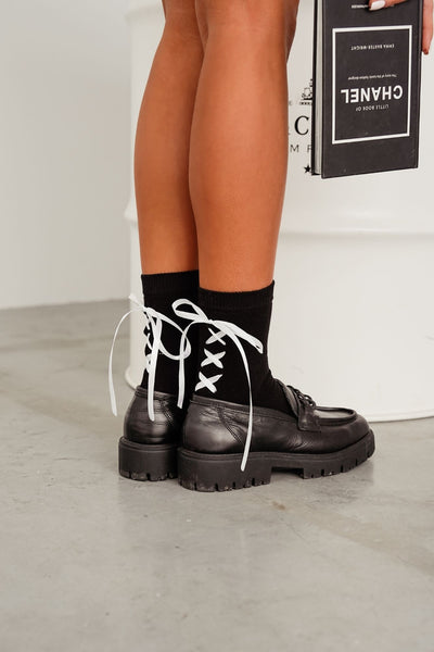 Black lace-trim cotton socks styled with shoes – side view showing ribbon heel and lace edge
