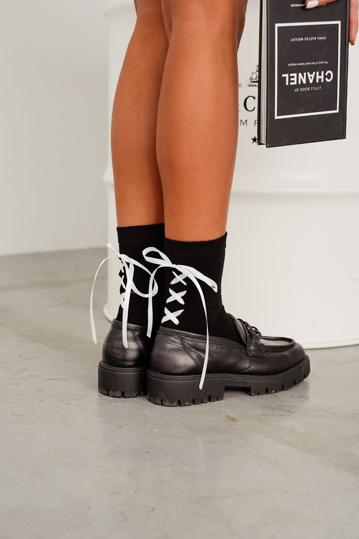 Black lace-trim cotton socks styled with shoes – side view showing ribbon heel and lace edge
