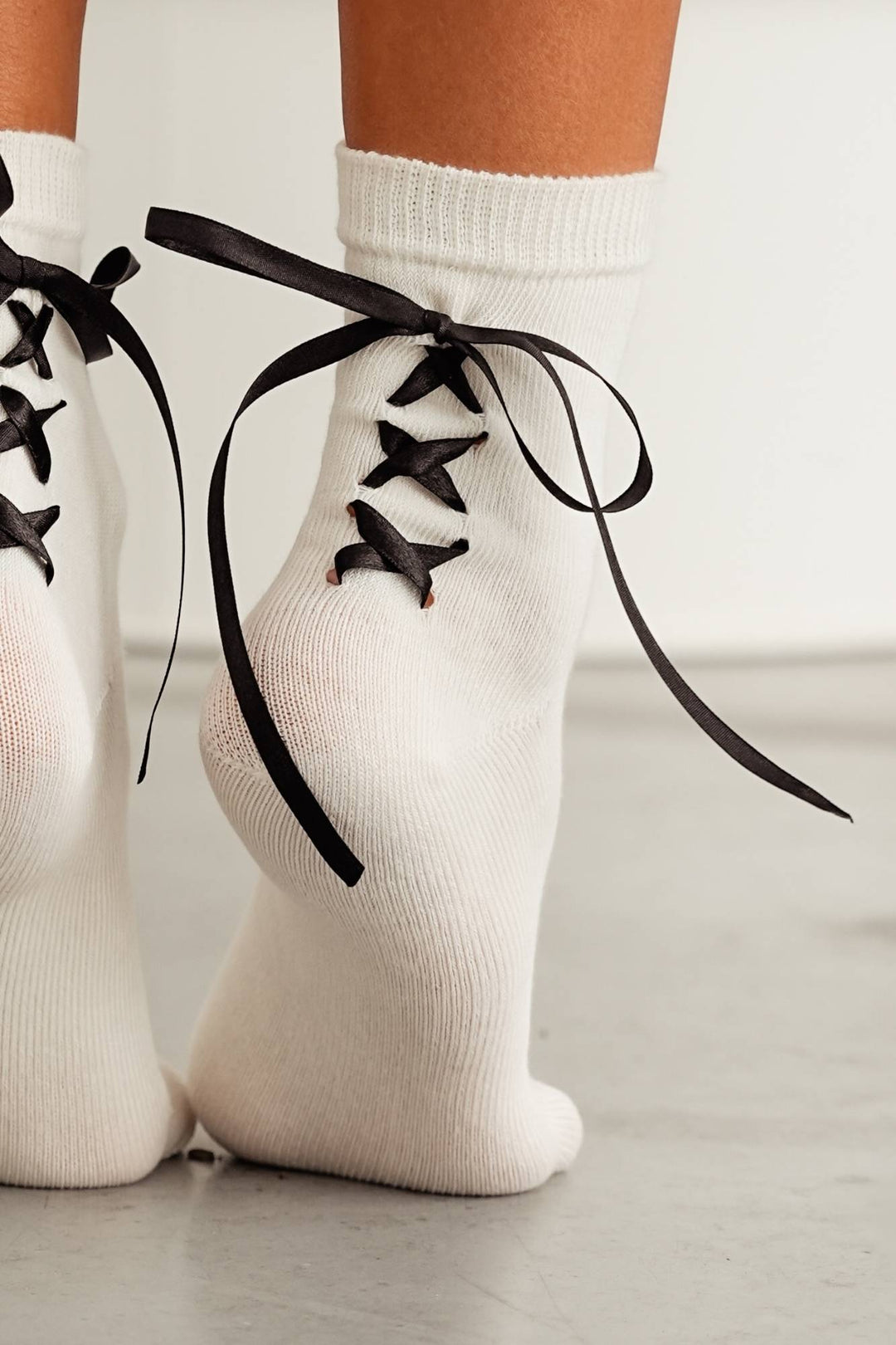 Close-up of ecru laced cotton socks – ribbon heel and lace trim detail on soft cotton fabric
