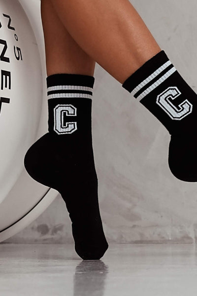 Close-up of white and black cotton socks with letter C – initial print detail on soft fabric
