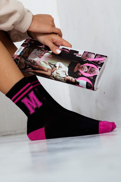 Close-up of black cotton socks with white letter M – bold initial print detail on soft fabric
