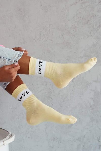 Yellow cotton socks with "Love" text print – side view showing slogan and ankle fit
