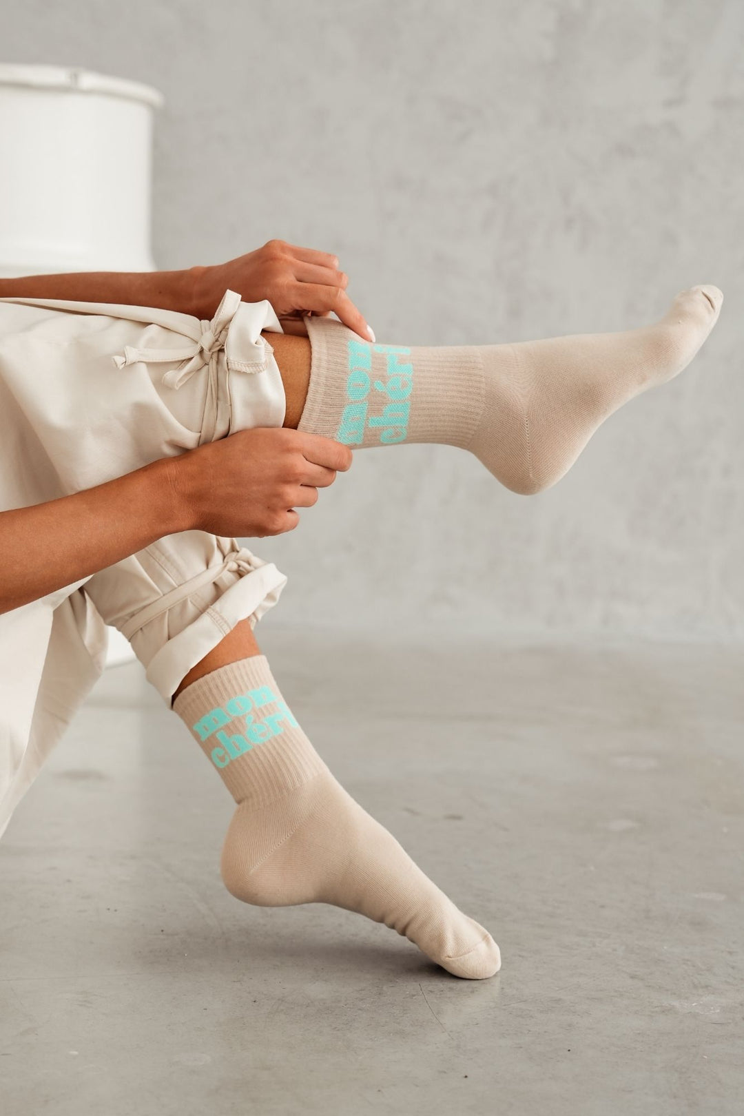 Beige cotton socks with Mon Chéri text print – side view showing pattern and sock length
