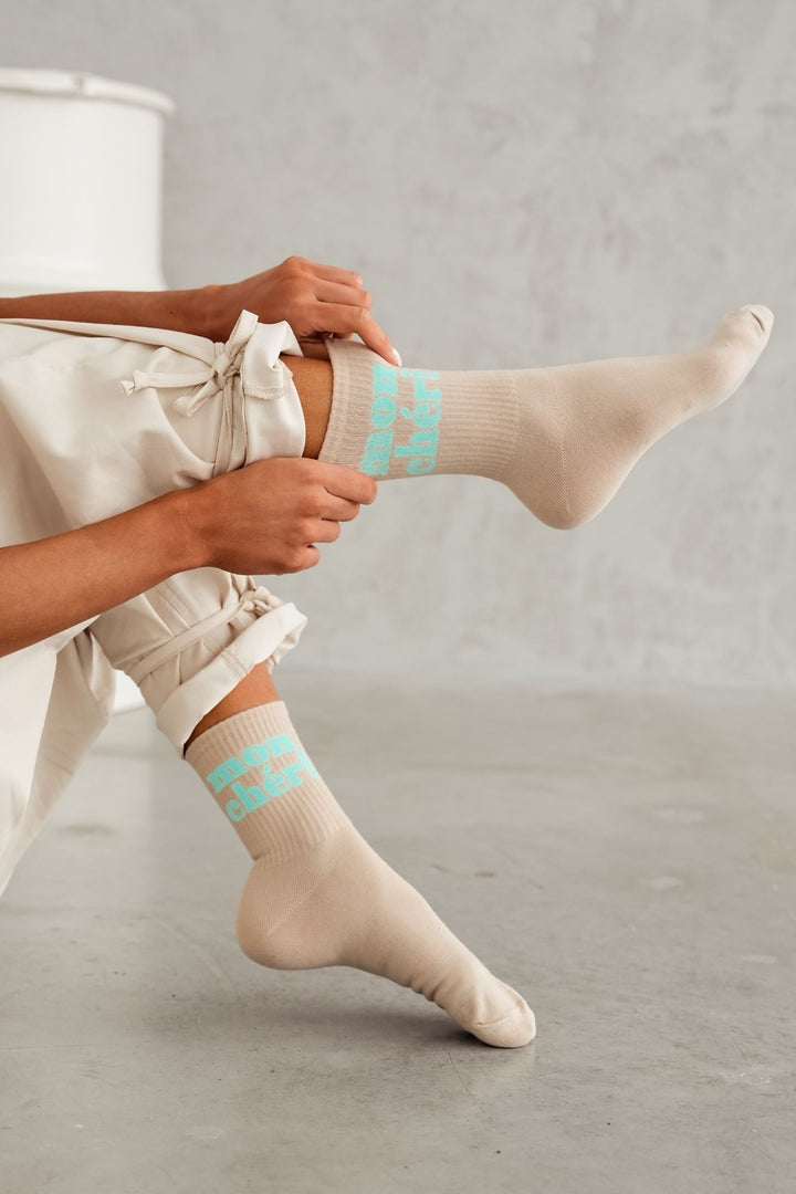Beige cotton socks with Mon Chéri text print – side view showing pattern and sock length
