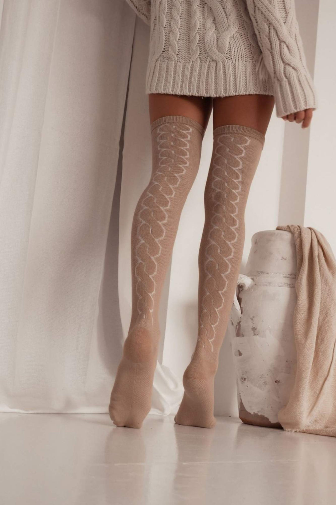 Beige openwork over-knee socks with back braid detail – back view showing intricate pattern and full length
