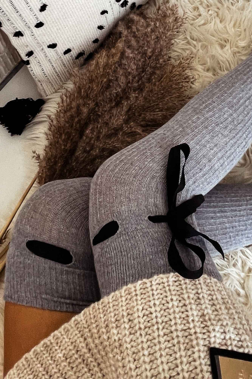 Close-up of light melange ribbed openwork over-knee socks – delicate knit pattern and ribbon tie detail
