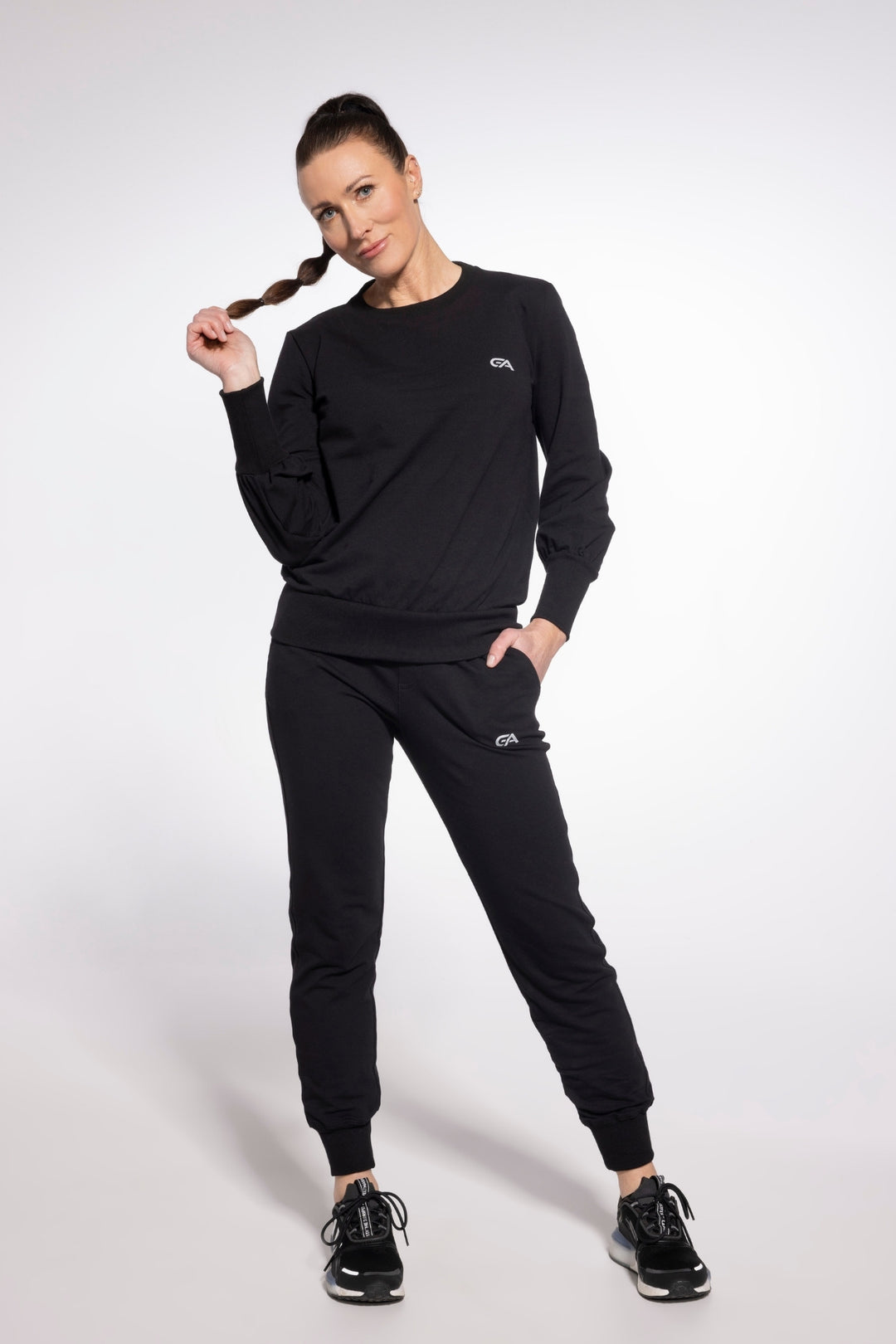Woman wearing a black tracksuit with a logo on a white background