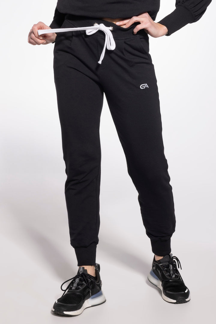 Person wearing black jogger pants with a brand logo on a white background