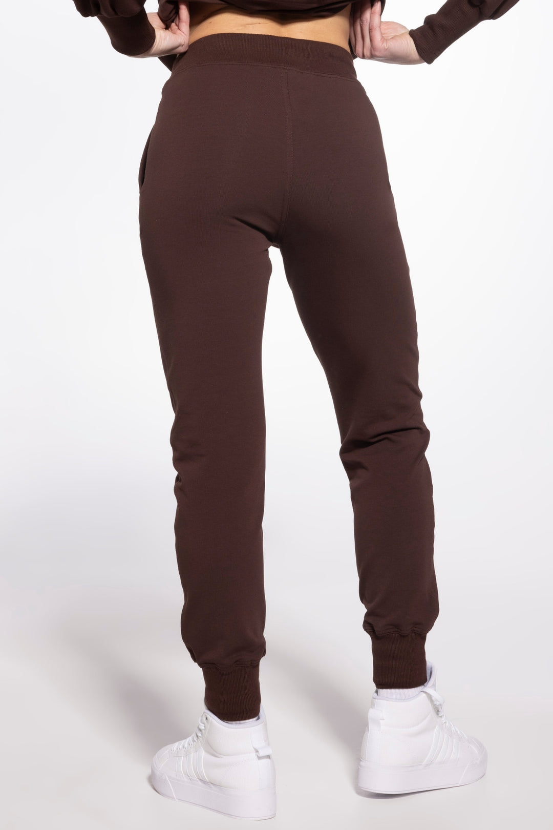 Brown sweatpants worn by a person on a white background