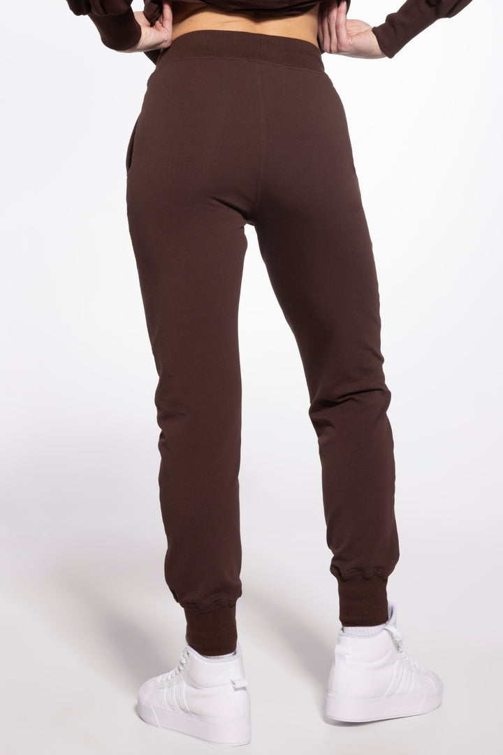 Brown sweatpants worn by a person on a white background
