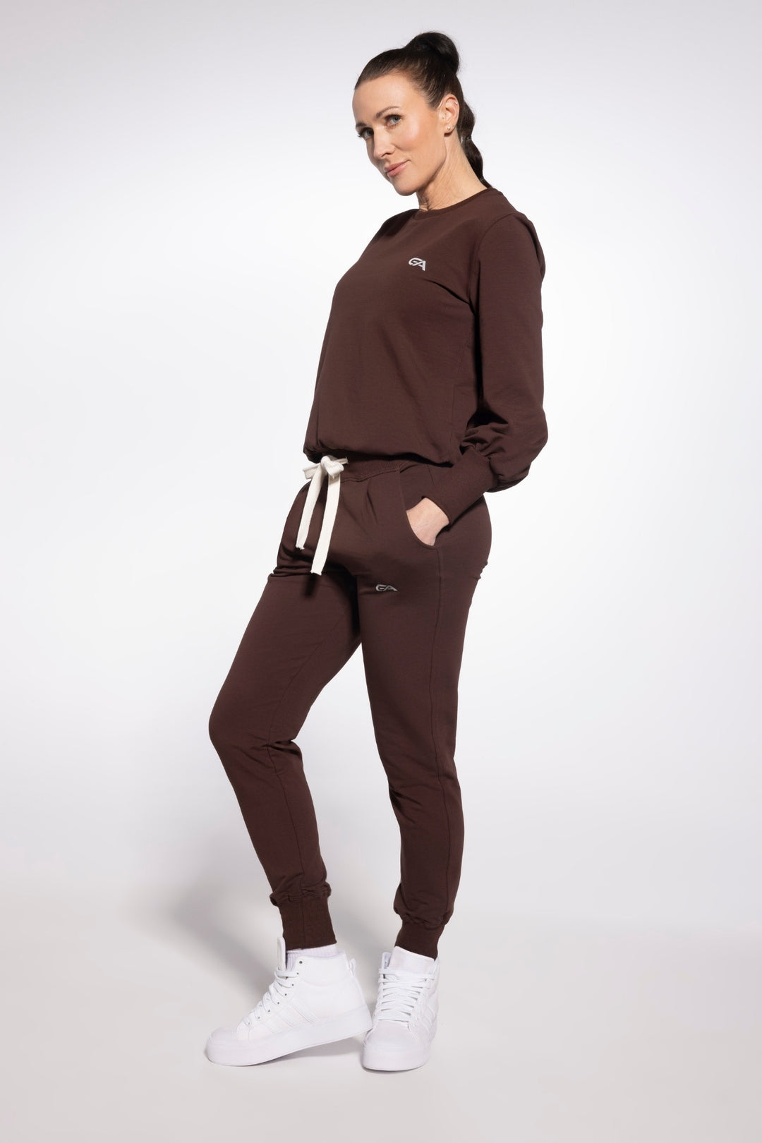 Woman wearing a brown tracksuit with a logo on a white background