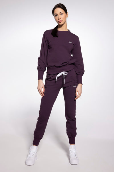 Model in the Gatta plum purple sweatpants and matching sweatshirt, full-length front view.