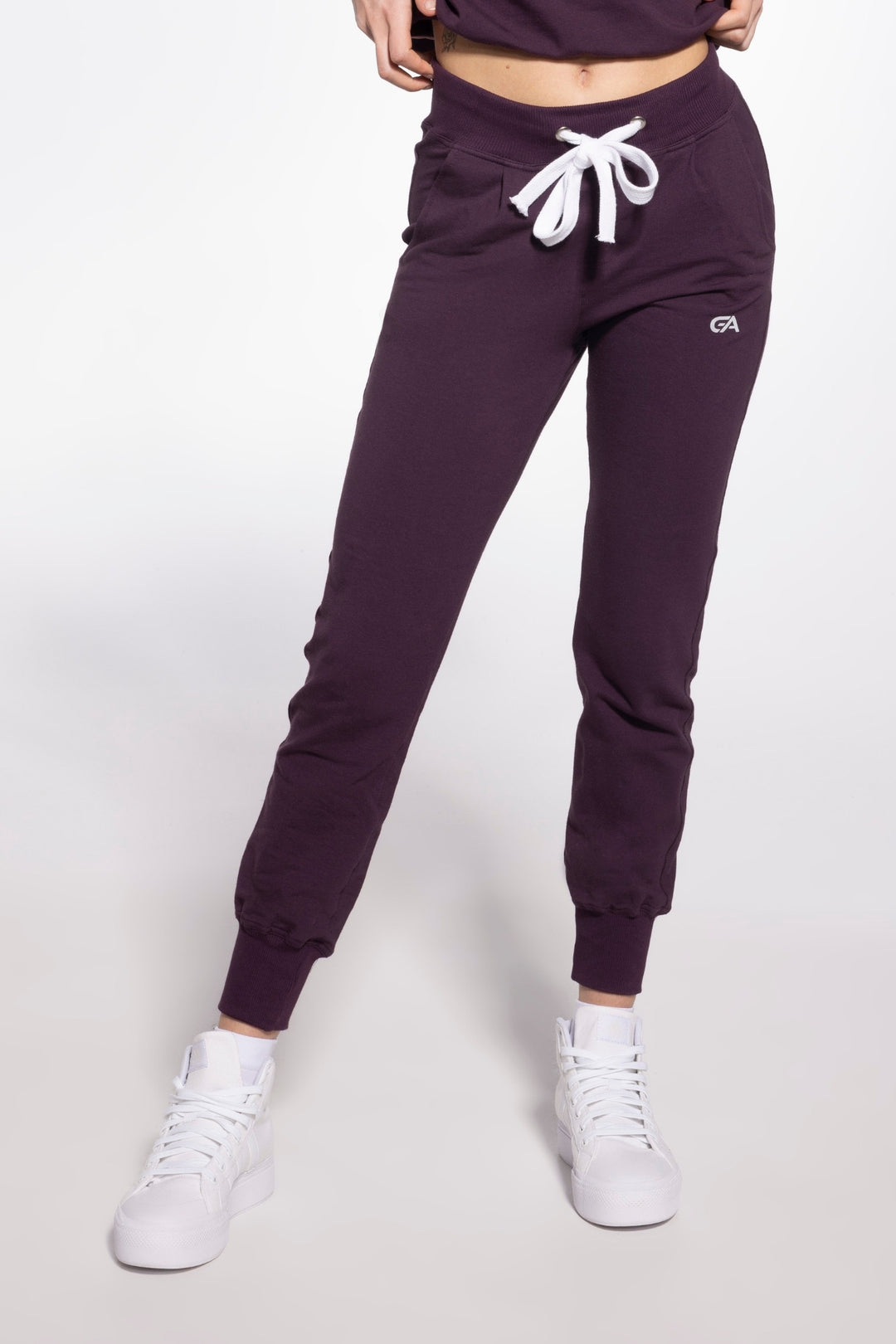 Purple jogger pants with white drawstrings and logo on a white background