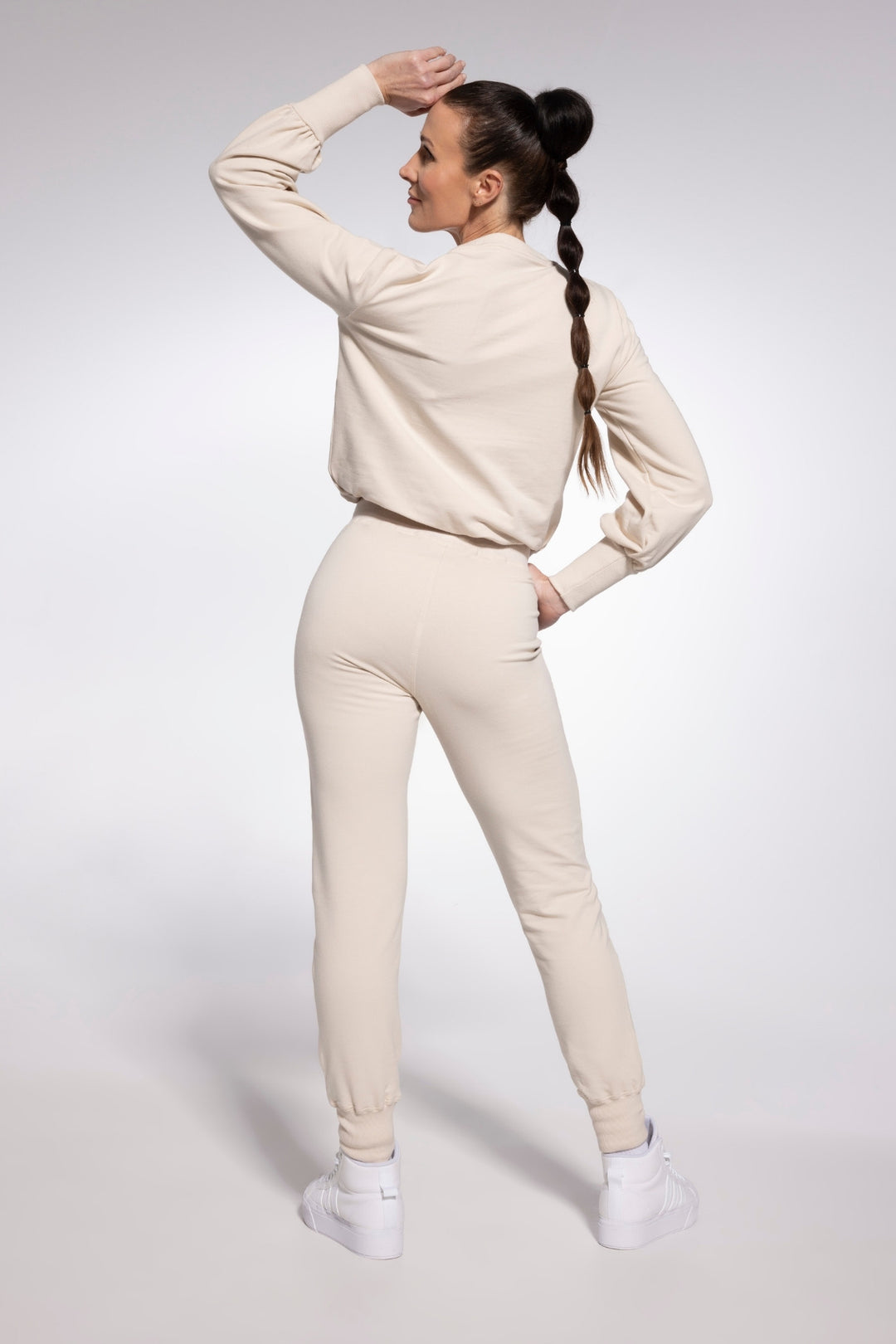 Woman wearing a beige tracksuit on a white background