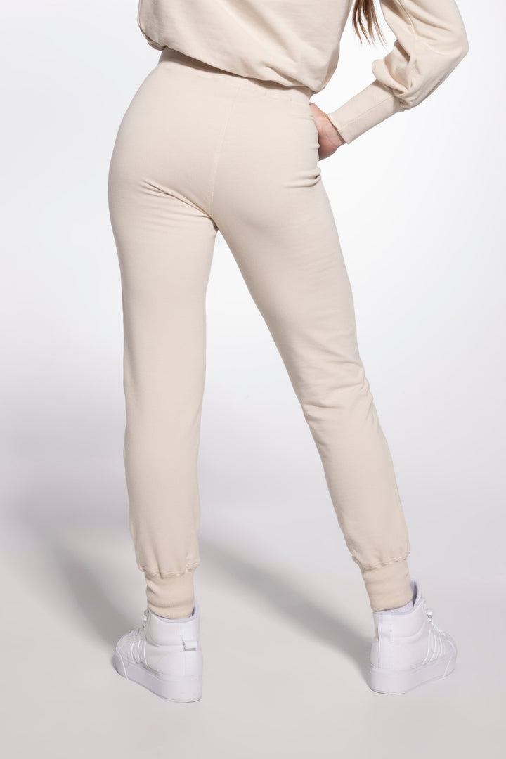 Person wearing beige jogger pants and a matching top on a white background