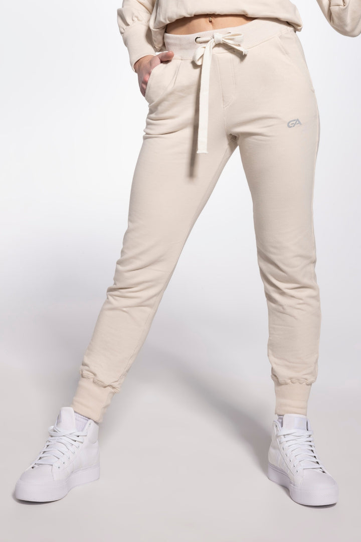 Beige jogger pants worn by a person on a white background