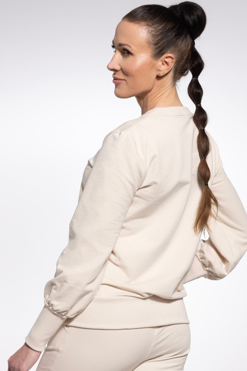 Woman wearing a beige outfit with a plain background