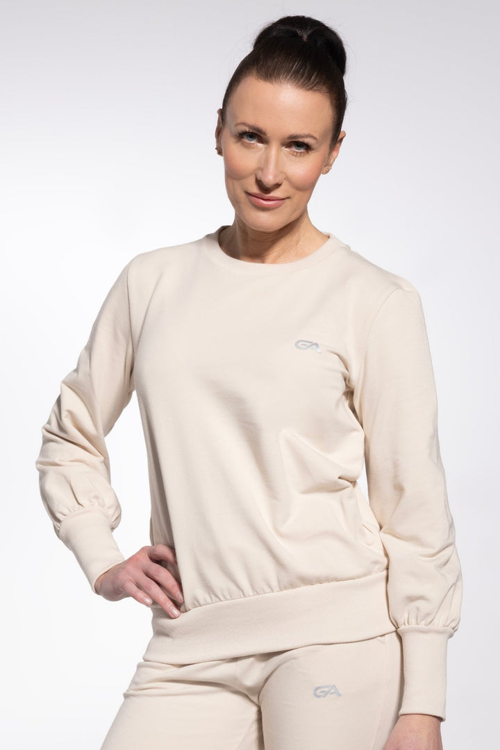 Woman wearing a beige sweatshirt and pants with a logo on a white background